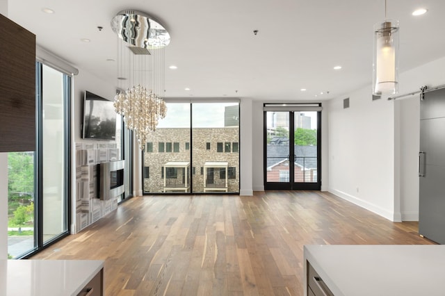 unfurnished living room featuring recessed lighting, baseboards, a notable chandelier, and light wood-type flooring