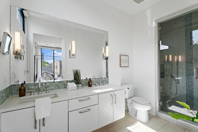 full bath with a sink, a shower stall, toilet, and double vanity