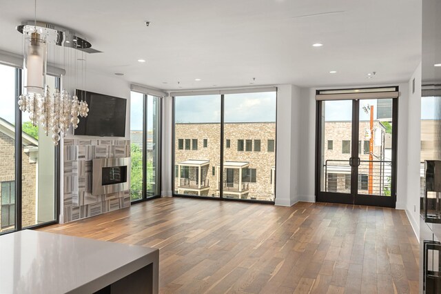 unfurnished living room featuring an inviting chandelier, a healthy amount of sunlight, and wood finished floors