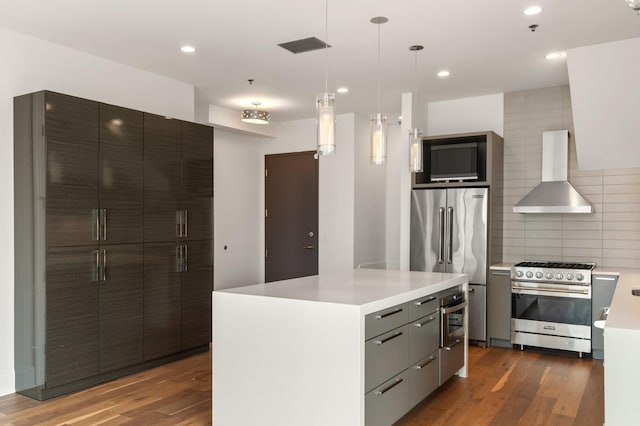 kitchen with wall chimney range hood, light countertops, dark wood finished floors, high end appliances, and decorative backsplash