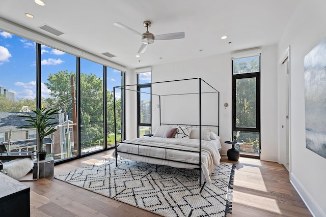 bedroom featuring visible vents, floor to ceiling windows, and wood finished floors