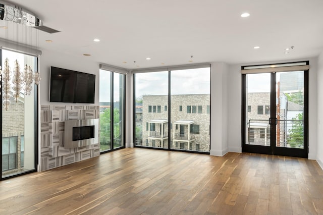 unfurnished living room featuring french doors, recessed lighting, wood finished floors, and a fireplace