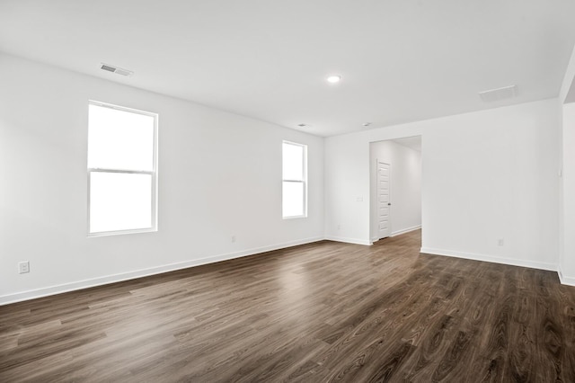 spare room featuring visible vents, recessed lighting, baseboards, and dark wood-type flooring
