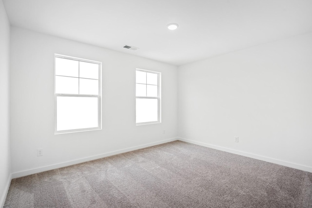 carpeted spare room featuring visible vents and baseboards