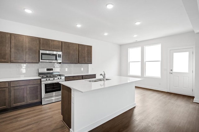 kitchen featuring decorative backsplash, light countertops, a sink, dark wood finished floors, and stainless steel appliances