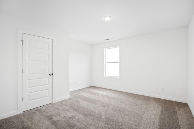 spare room with carpet floors, baseboards, and visible vents