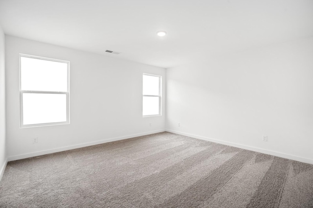 carpeted spare room featuring visible vents and baseboards