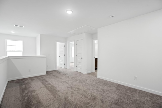 empty room featuring baseboards, carpet, attic access, and visible vents