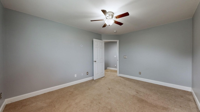 unfurnished room with baseboards, ceiling fan, and light carpet