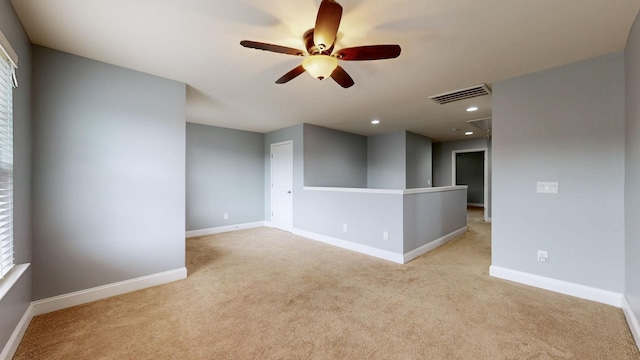 carpeted spare room featuring ceiling fan, attic access, baseboards, and visible vents