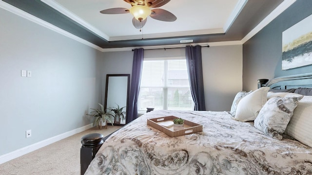carpeted bedroom featuring a tray ceiling, baseboards, ceiling fan, and ornamental molding