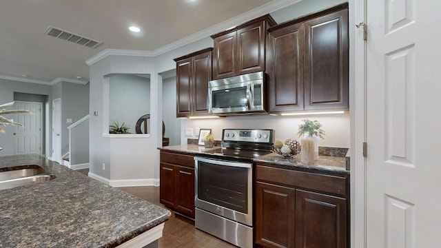 kitchen featuring dark brown cabinets, appliances with stainless steel finishes, dark stone countertops, recessed lighting, and visible vents