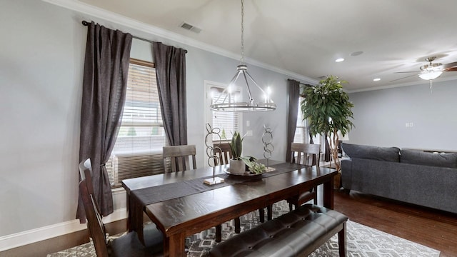 dining space featuring crown molding, visible vents, ceiling fan with notable chandelier, and dark wood-type flooring