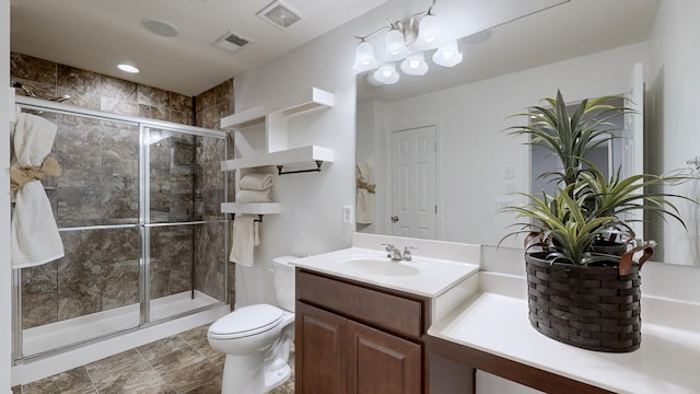 bathroom featuring toilet, visible vents, a shower stall, and vanity