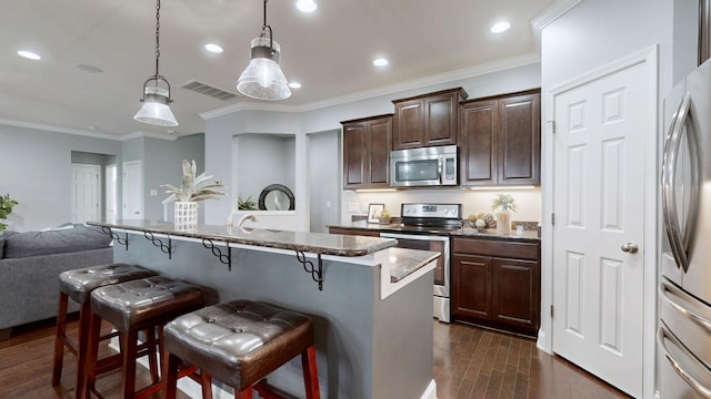 kitchen featuring dark wood-style flooring, a breakfast bar, stainless steel appliances, recessed lighting, and visible vents