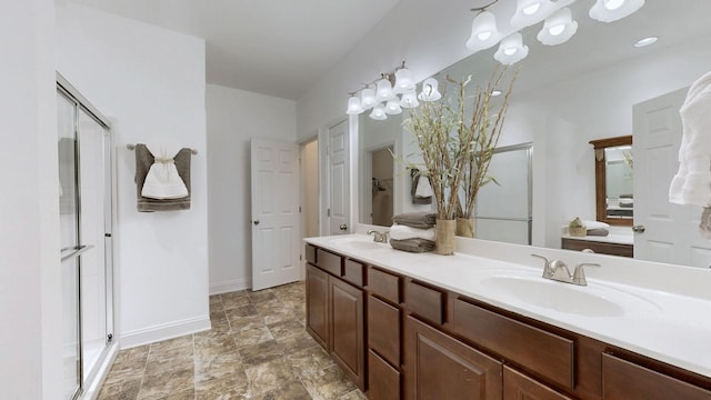 full bathroom featuring baseboards, a sink, double vanity, and a shower stall