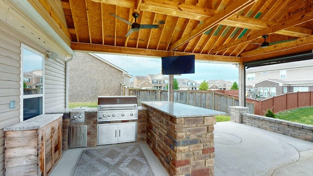 view of patio with area for grilling, exterior kitchen, a ceiling fan, and a fenced backyard