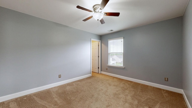spare room featuring baseboards, a ceiling fan, visible vents, and light colored carpet