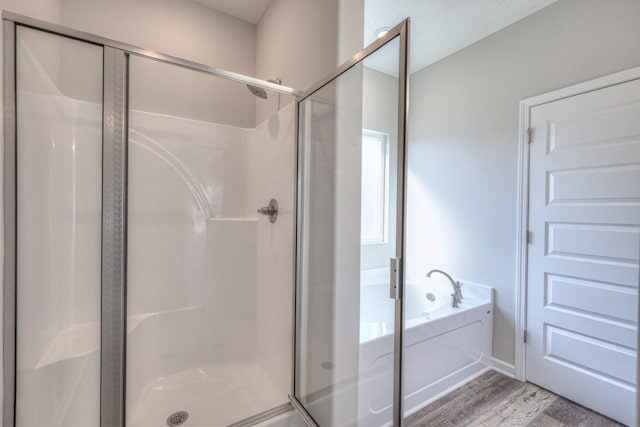 full bath with a bath, a stall shower, and wood finished floors