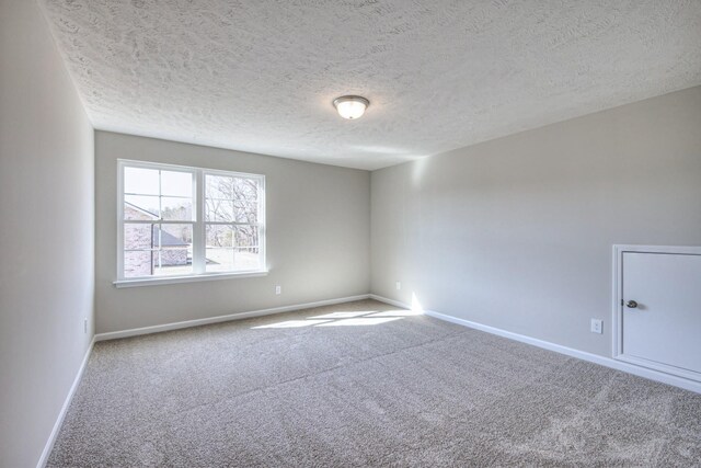 spare room featuring carpet flooring, a textured ceiling, and baseboards