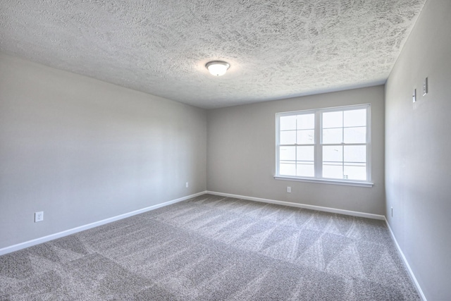 carpeted empty room featuring baseboards and a textured ceiling