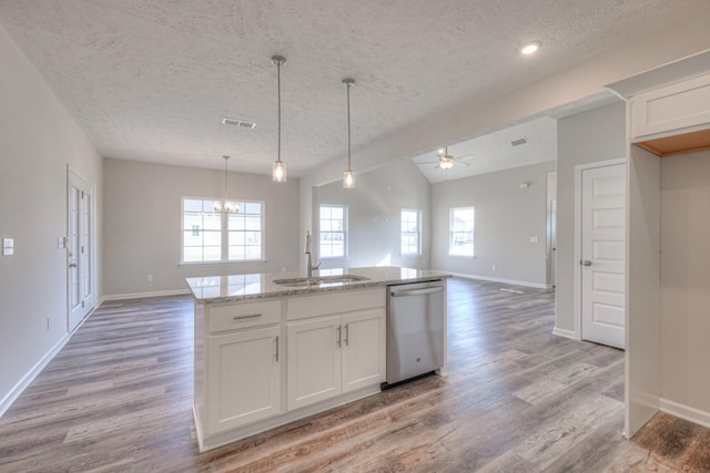 kitchen featuring stainless steel dishwasher, a sink, a textured ceiling, and open floor plan