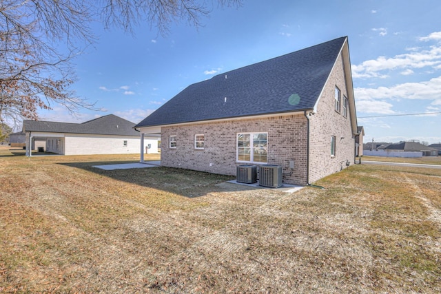 rear view of house with a lawn, a shingled roof, brick siding, and cooling unit