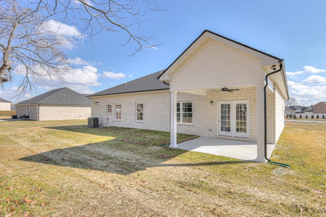 back of property featuring brick siding, ceiling fan, central AC unit, a patio, and a yard