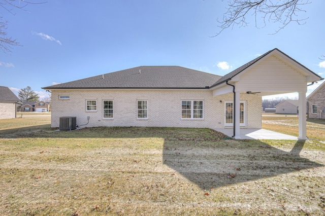 rear view of house with a yard, brick siding, cooling unit, and a patio area