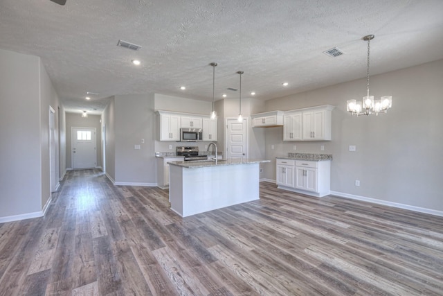 kitchen with a textured ceiling, visible vents, appliances with stainless steel finishes, wood finished floors, and white cabinetry