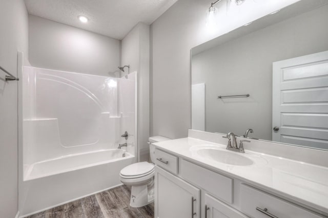 full bath with a textured ceiling, wood finished floors, vanity, toilet, and  shower combination