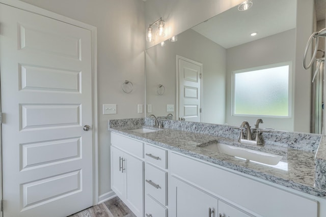 bathroom featuring double vanity, a sink, and wood finished floors