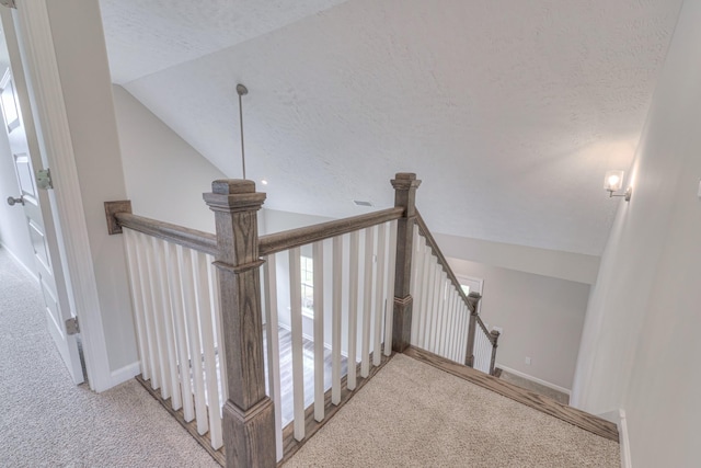 stairway with visible vents, lofted ceiling, baseboards, a textured ceiling, and carpet flooring