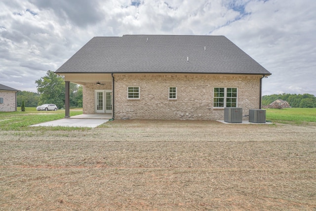 rear view of house with brick siding, a patio area, roof with shingles, and french doors