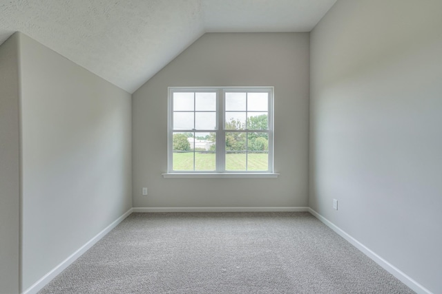 unfurnished room featuring carpet flooring, baseboards, and lofted ceiling