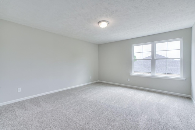 carpeted empty room with baseboards and a textured ceiling