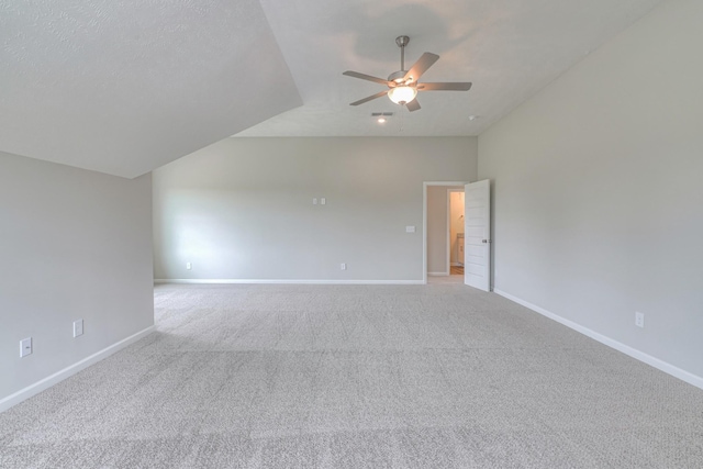 unfurnished room with a ceiling fan, visible vents, vaulted ceiling, baseboards, and light carpet
