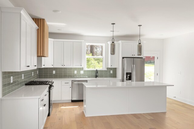 kitchen featuring backsplash, stainless steel appliances, a kitchen island, and light wood finished floors