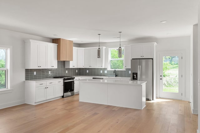 kitchen featuring light wood-style floors, a kitchen island, stainless steel appliances, and white cabinetry