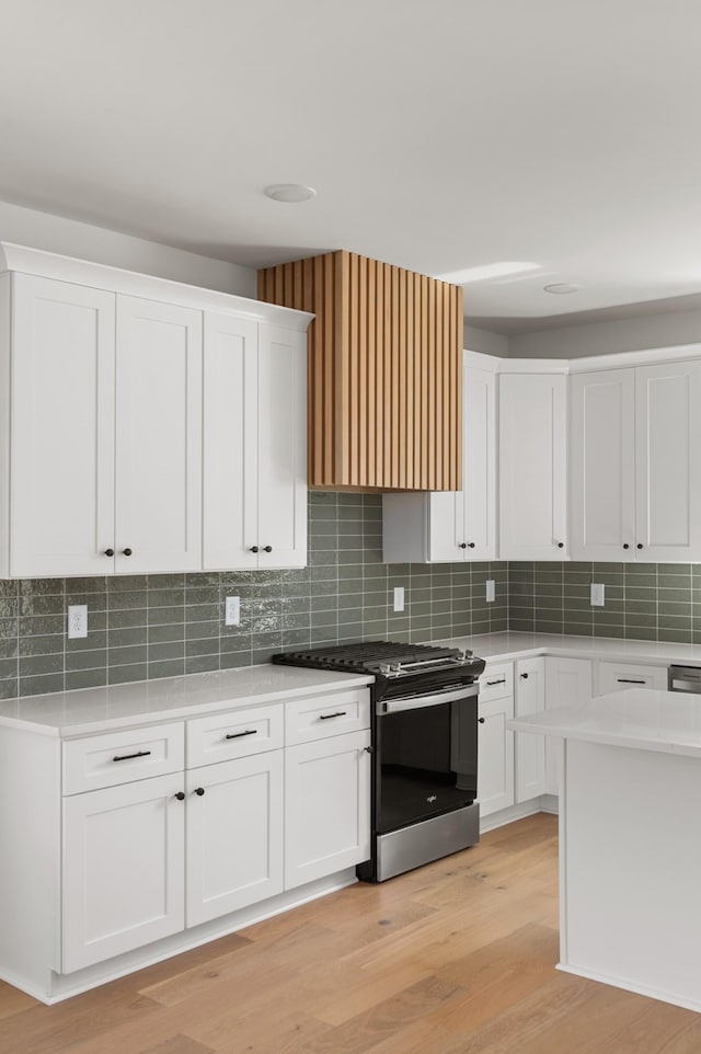 kitchen featuring light countertops, light wood finished floors, stainless steel gas stove, and white cabinetry