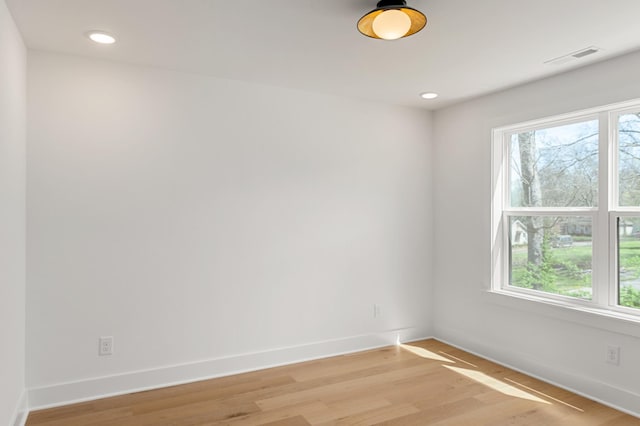 spare room featuring baseboards, a wealth of natural light, and light wood-style flooring