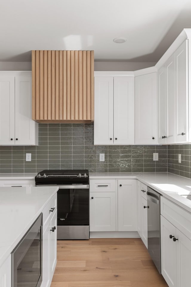 kitchen with beverage cooler, appliances with stainless steel finishes, and white cabinetry