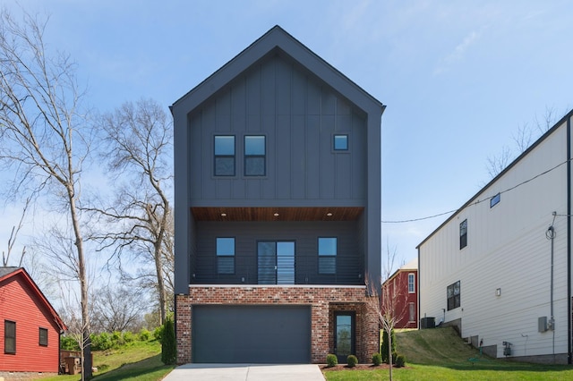 contemporary home featuring a front yard, brick siding, board and batten siding, an attached garage, and driveway