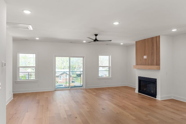 unfurnished living room with ceiling fan, light wood-type flooring, baseboards, a glass covered fireplace, and recessed lighting