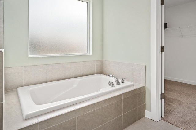 bathroom with tile patterned flooring, a spacious closet, and a garden tub