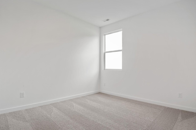 empty room featuring baseboards, light carpet, and visible vents
