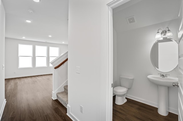 half bath with visible vents, wood finished floors, baseboards, toilet, and recessed lighting