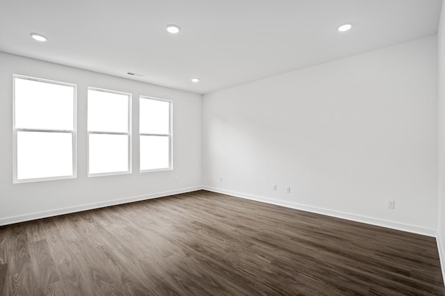 spare room with dark wood-style flooring, baseboards, and recessed lighting