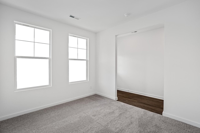 empty room with baseboards, plenty of natural light, and dark colored carpet