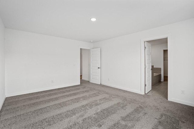 unfurnished bedroom featuring baseboards, recessed lighting, connected bathroom, tile patterned floors, and carpet flooring